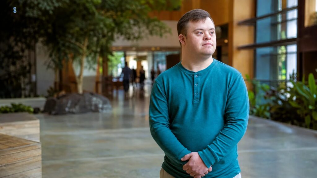 Young man with developmental disability stands alone staring thoughtfully.