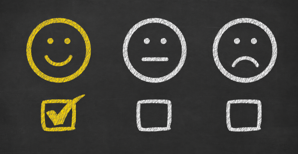 healthy unhealthy unsafe A chalkboard-style graphic shows three faces representing emotions: a sad face, a neutral face, and a smiling face. Below each face is a checkbox. Only the checkbox beneath the smiling face is checked with a yellow checkmark, suggesting a positive choice or satisfaction.