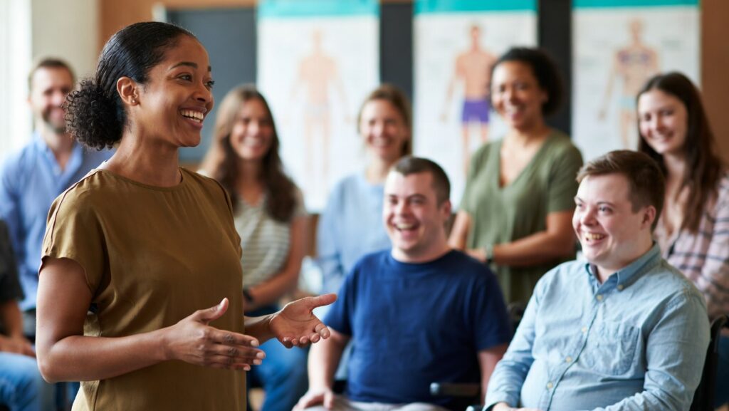 Diverse group of self-advocates, parents, and professionals smiling and learning together in an Elevatus Training workshop on understanding your body and sexual anatomy.